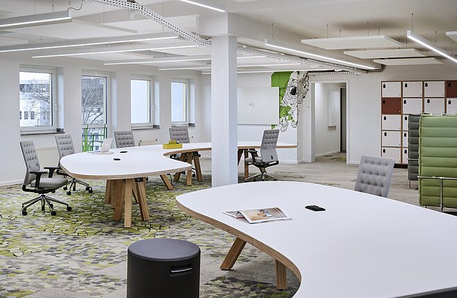 Ein offenes Büro im L64 der AWO mit weißen und grünen Stühlen und Tischen.