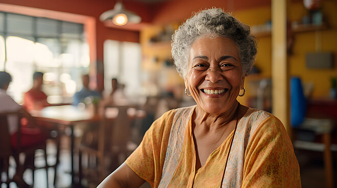 Eine ältere Frau lächelt in einem Restaurant.
