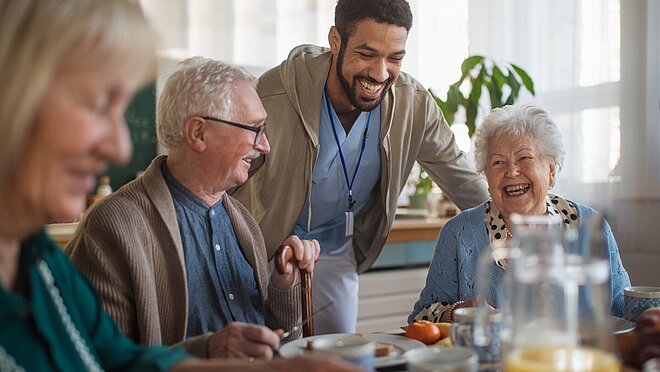 Eine Betreuungsgruppe von Senior:innen frühstückt in einer Tagespflegeeinrichtung der AWO Mönchengladbach und erhält Unterstützung.