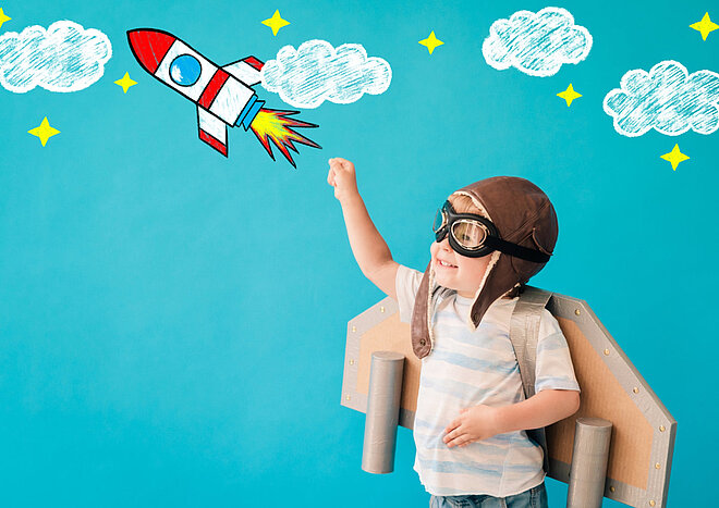 Ein als Rakete verkleideter Junge zeigt in den Himmel bei einer AWO-Kitas-Veranstaltung.