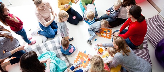 Eine Gruppe von Frauen und Kindern sitzt auf dem Boden im Mütterzentrum der AWO in Mönchengladbach.
