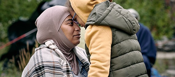 Eine Frau im Hijab umarmt ein Kind.