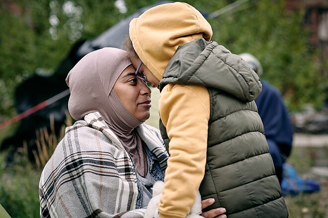 Eine Frau im Hijab umarmt ein Kind.